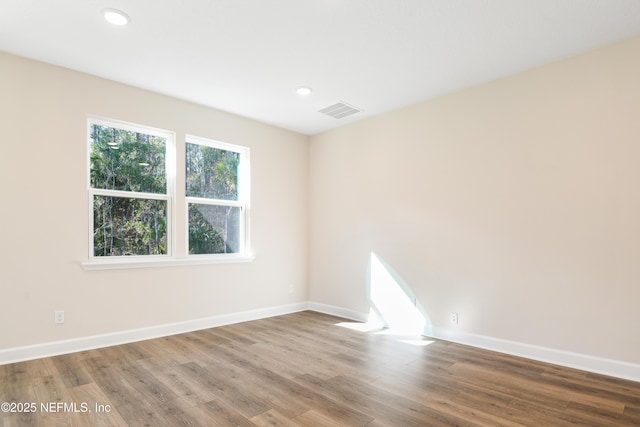 spare room featuring recessed lighting, visible vents, baseboards, and wood finished floors