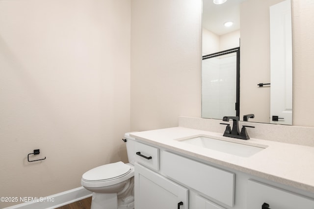 full bath featuring toilet, wood finished floors, vanity, baseboards, and a tile shower