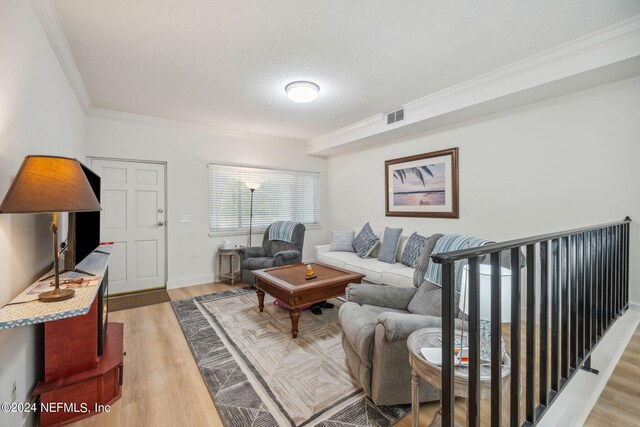 living room with a textured ceiling, hardwood / wood-style floors, and crown molding