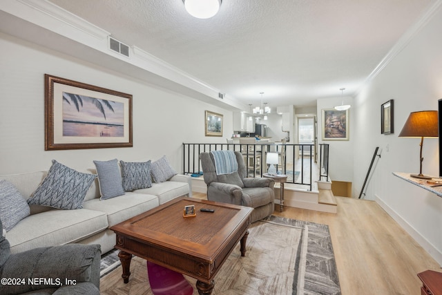 living room featuring a textured ceiling, crown molding, light wood-type flooring, and a chandelier