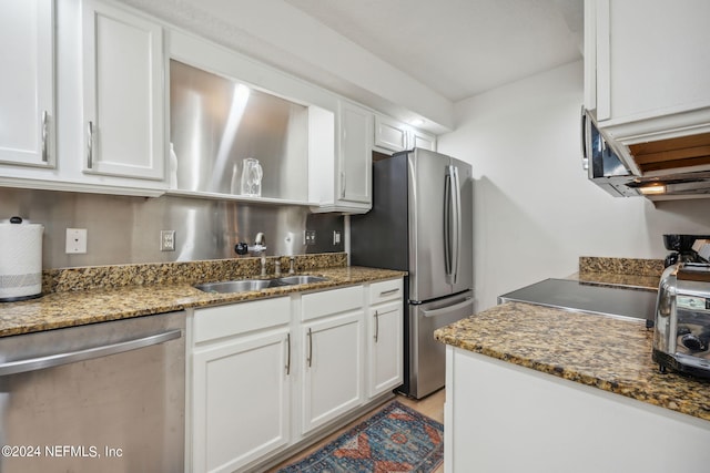 kitchen featuring dark stone countertops, white cabinetry, and stainless steel appliances