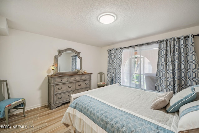 bedroom featuring light hardwood / wood-style floors and a textured ceiling