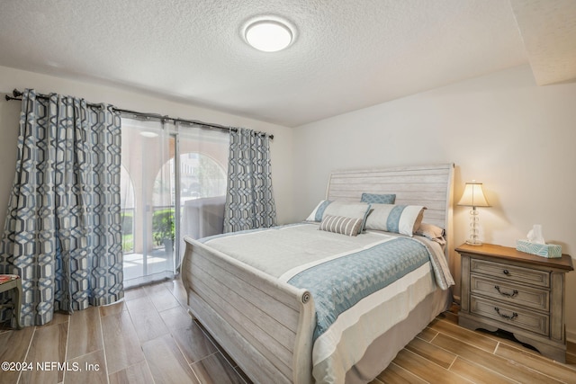 bedroom featuring a textured ceiling, access to outside, and light hardwood / wood-style floors