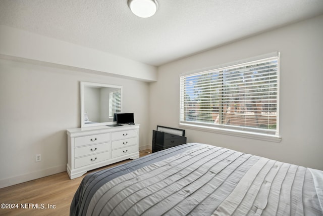 bedroom with light wood-type flooring and a textured ceiling