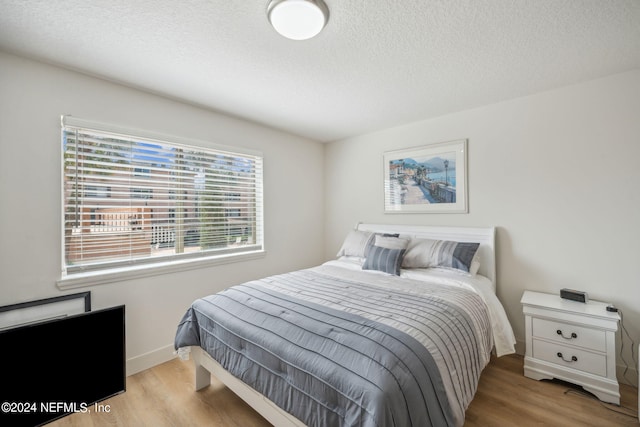 bedroom with light wood-type flooring and a textured ceiling