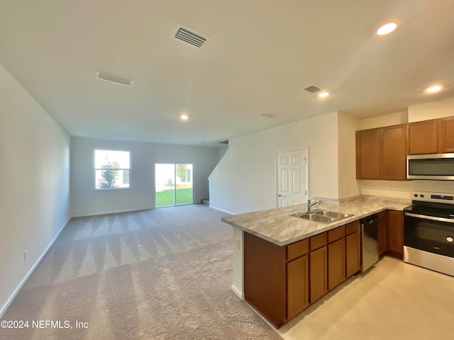 kitchen featuring appliances with stainless steel finishes, kitchen peninsula, sink, and light colored carpet