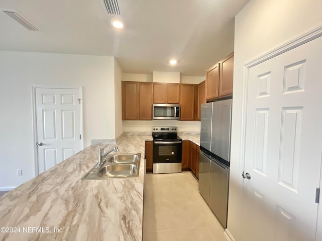 kitchen featuring stainless steel appliances, light stone counters, light tile patterned floors, and sink