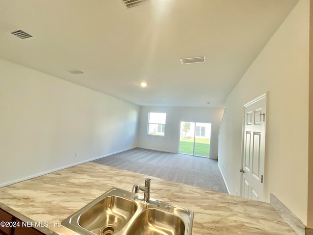 kitchen with light colored carpet, lofted ceiling, and sink