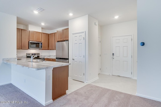 kitchen featuring sink, light carpet, appliances with stainless steel finishes, a kitchen breakfast bar, and kitchen peninsula