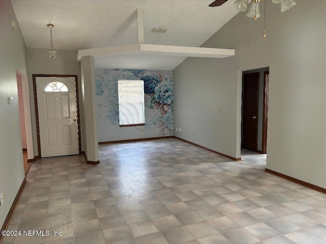 foyer entrance featuring a textured ceiling, high vaulted ceiling, and ceiling fan with notable chandelier