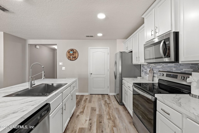 kitchen with white cabinetry, light hardwood / wood-style floors, appliances with stainless steel finishes, and sink