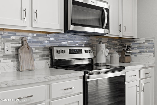 kitchen featuring appliances with stainless steel finishes, backsplash, white cabinetry, and light stone countertops