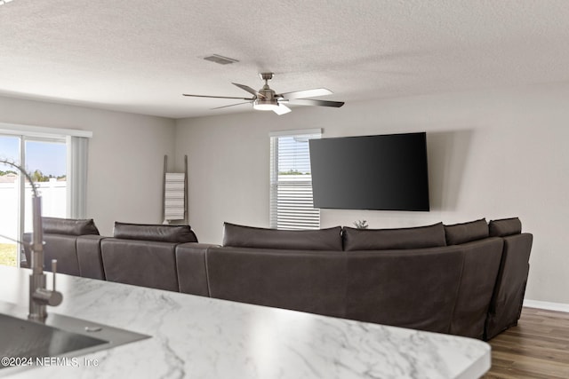 living room with a textured ceiling, hardwood / wood-style floors, ceiling fan, and sink