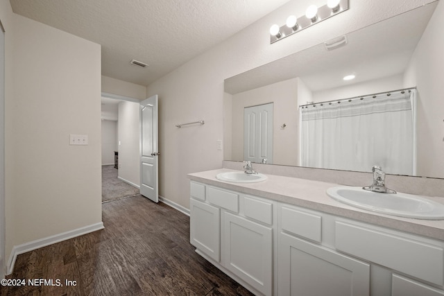 bathroom with a textured ceiling, wood-type flooring, and vanity