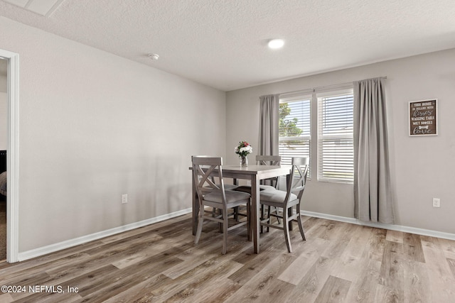 dining area featuring light wood-type flooring and a textured ceiling