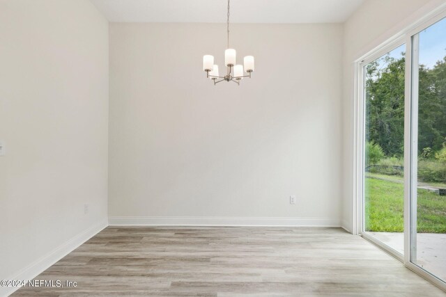 unfurnished room with a notable chandelier and light hardwood / wood-style flooring