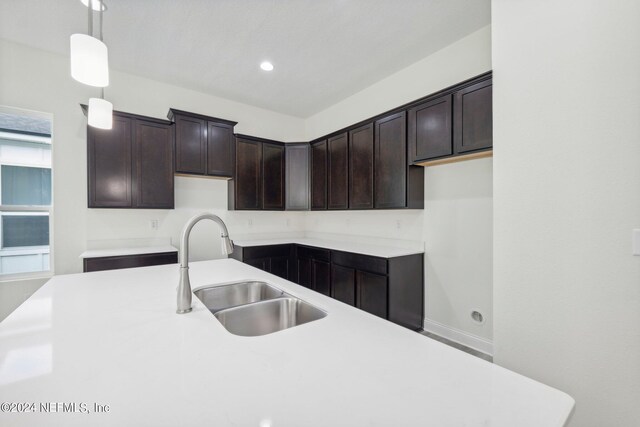 kitchen featuring pendant lighting, dark brown cabinetry, and sink