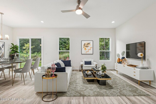 living room featuring ceiling fan with notable chandelier and hardwood / wood-style floors