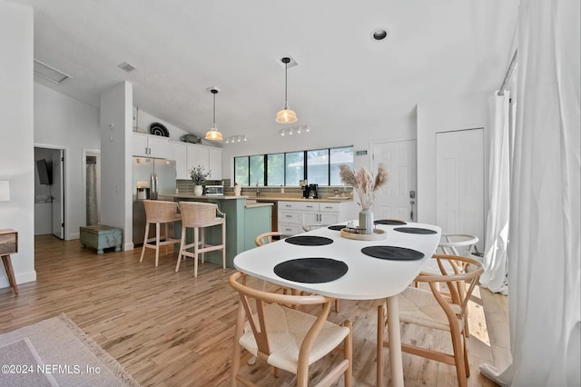 dining room featuring sink, light hardwood / wood-style flooring, and vaulted ceiling