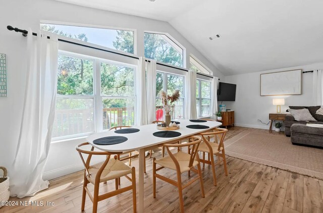 dining area with light hardwood / wood-style floors and vaulted ceiling