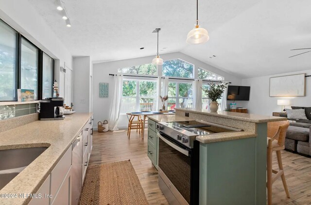 kitchen with vaulted ceiling, white cabinets, pendant lighting, stainless steel appliances, and light hardwood / wood-style flooring