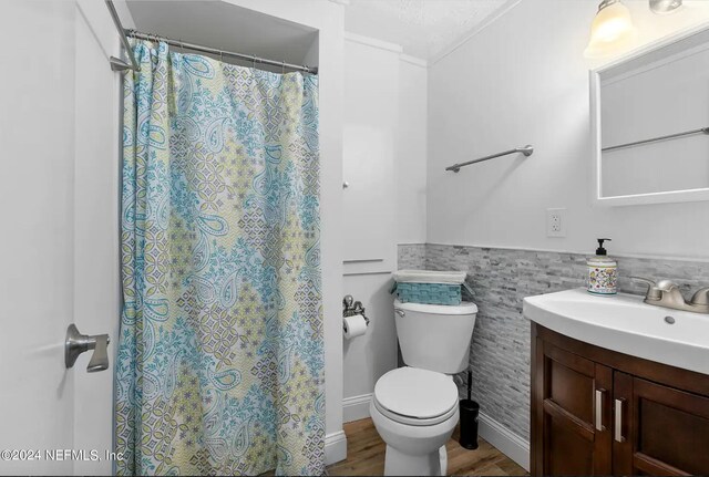 bathroom featuring tile walls, hardwood / wood-style flooring, a shower with shower curtain, vanity, and toilet