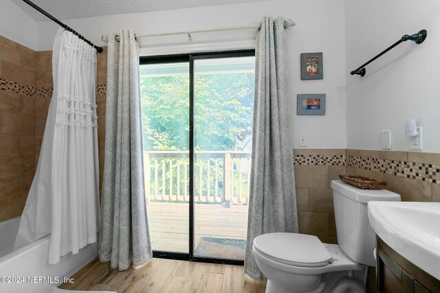 full bathroom featuring tile walls, wood-type flooring, shower / bath combo, vanity, and toilet