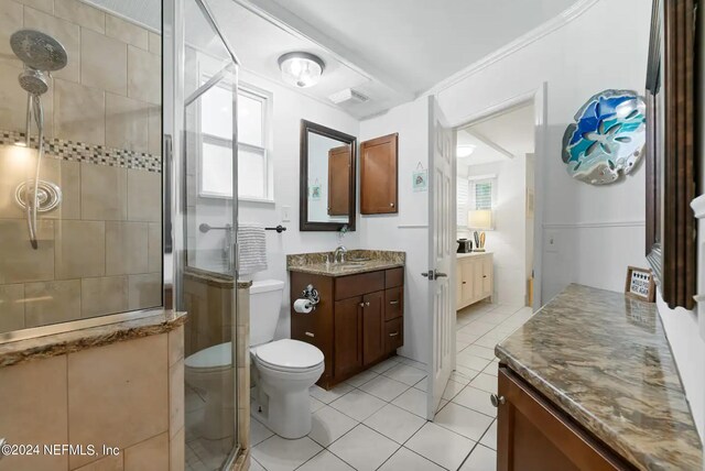 bathroom with a healthy amount of sunlight, vanity, toilet, and a shower with shower door