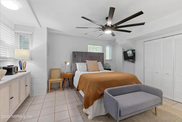 tiled bedroom featuring ceiling fan and a closet