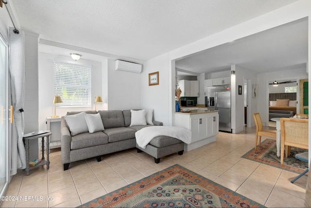 living room with an AC wall unit, ceiling fan, light tile patterned floors, and a textured ceiling