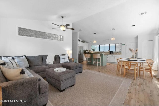 living room featuring lofted ceiling, light hardwood / wood-style floors, and ceiling fan