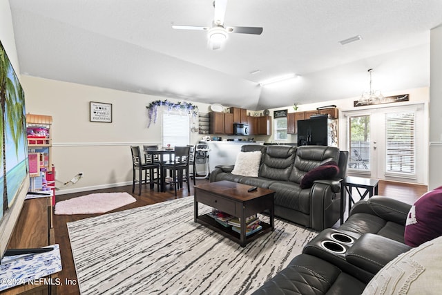 living room featuring ceiling fan with notable chandelier, light hardwood / wood-style floors, vaulted ceiling, and a healthy amount of sunlight