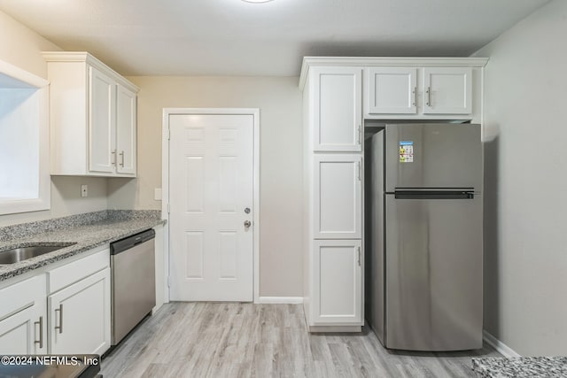 kitchen featuring light stone counters, stainless steel appliances, light hardwood / wood-style floors, and white cabinetry