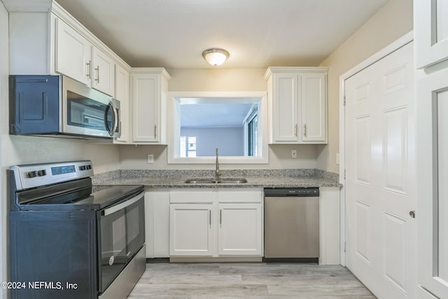 kitchen featuring appliances with stainless steel finishes, sink, light hardwood / wood-style floors, and white cabinets