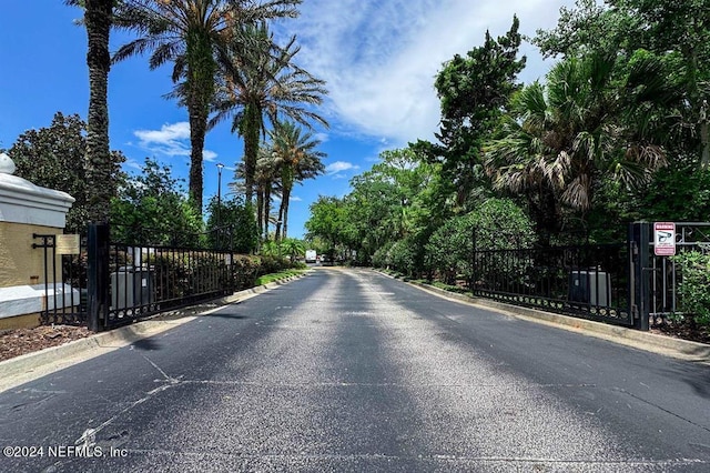 view of street featuring a gated entry, curbs, and a gate