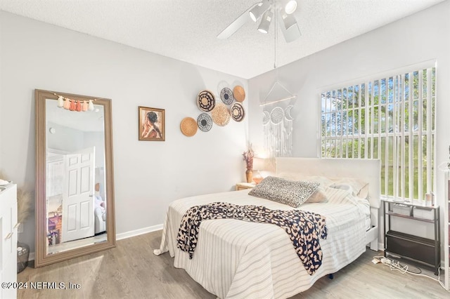 bedroom with wood finished floors, a textured ceiling, and ceiling fan