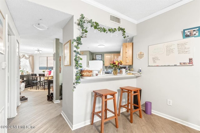 bar featuring baseboards, visible vents, a textured ceiling, and light wood-style floors