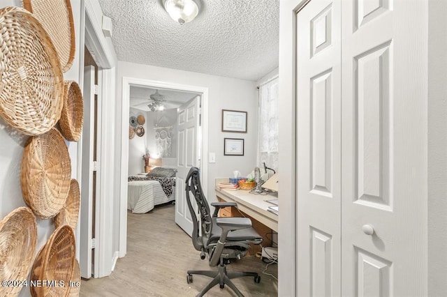 office area with light wood-style floors and a textured ceiling