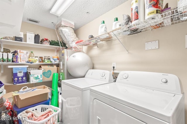 washroom with a textured ceiling, visible vents, washer and dryer, and laundry area