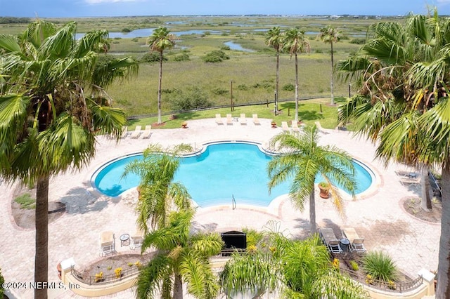 pool featuring a water view and a patio area