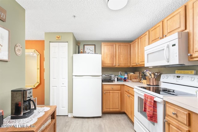 kitchen with light wood finished floors, light countertops, white appliances, and a wood stove