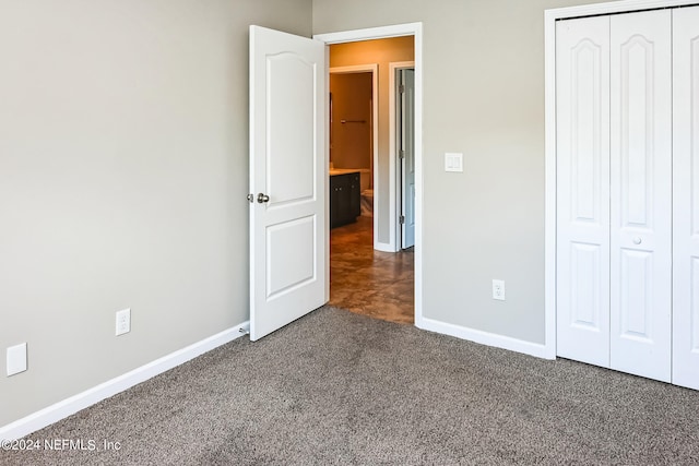 unfurnished bedroom featuring a closet and dark carpet