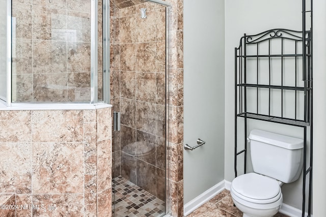 bathroom featuring toilet, tile patterned floors, and an enclosed shower