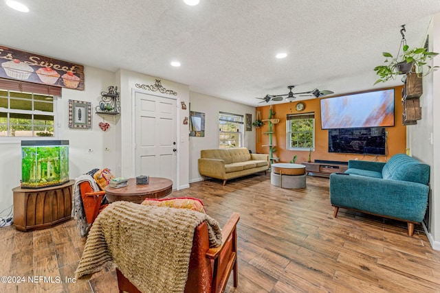 living room with ceiling fan, a textured ceiling, plenty of natural light, and hardwood / wood-style floors