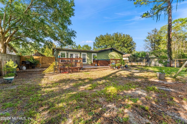 rear view of property with a wooden deck and a lawn