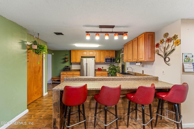 kitchen featuring stainless steel appliances, a textured ceiling, tasteful backsplash, and dark hardwood / wood-style flooring