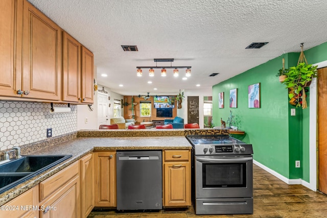 kitchen with tasteful backsplash, kitchen peninsula, dark hardwood / wood-style flooring, stainless steel appliances, and a textured ceiling