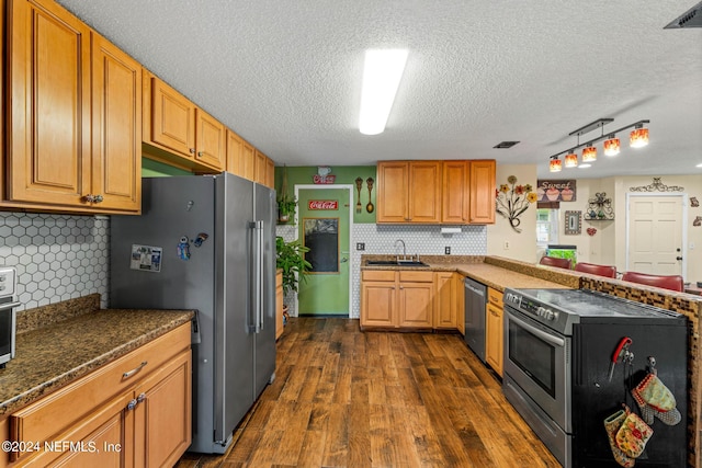 kitchen with a textured ceiling, dark hardwood / wood-style floors, sink, backsplash, and appliances with stainless steel finishes