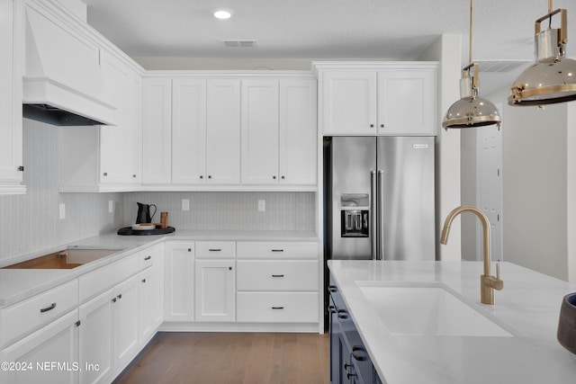 kitchen featuring hanging light fixtures, premium range hood, sink, and white cabinets