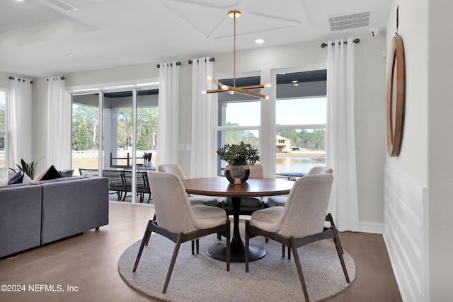 dining space featuring a notable chandelier, wood-type flooring, a water view, and plenty of natural light